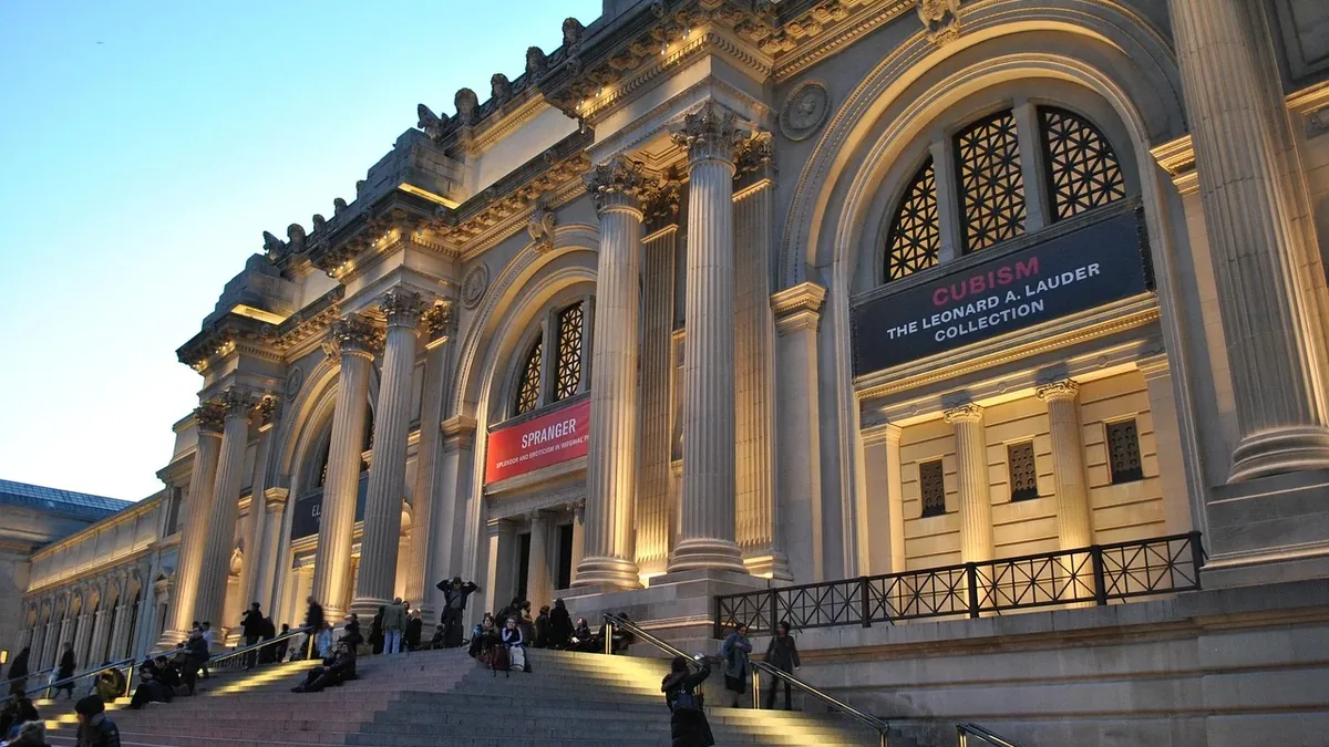 The Metropolitan Museum of Art in New York City, with a large stone building featuring columns and arches, and a sign reading "The Met" and 