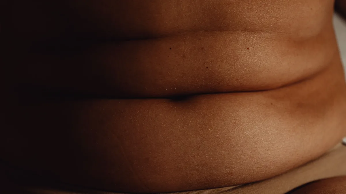 A close-up view of a person's lower torso, with their skin and clothing visible.